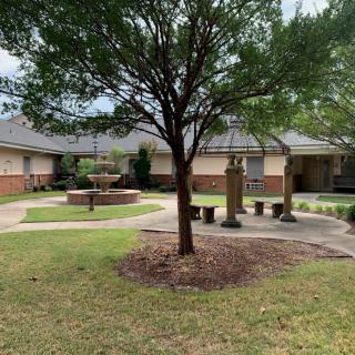 A quiet courtyard with a central tree, surrounded by benches and buildings.