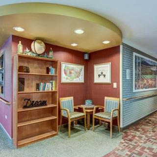 A cozy seating area with two chairs and decorative shelves in a warmly lit corner.