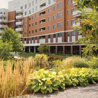 A modern apartment building surrounded by lush greenery and a well-maintained garden.