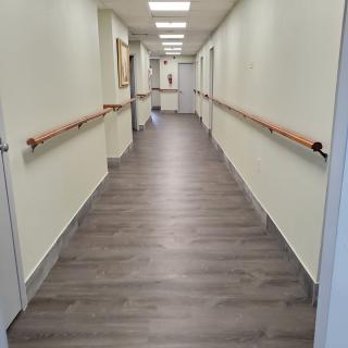 A long, well-lit hallway with handrails and wooden flooring.