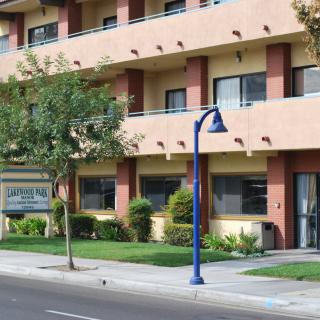 A street view of a multi-story hotel building with trees and a sidewalk in front.