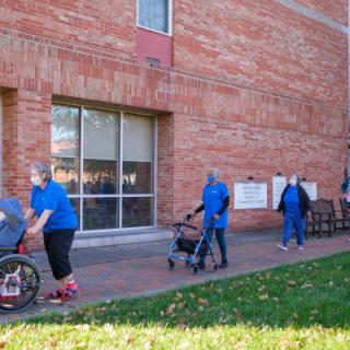 People walking with strollers outside a brick building.