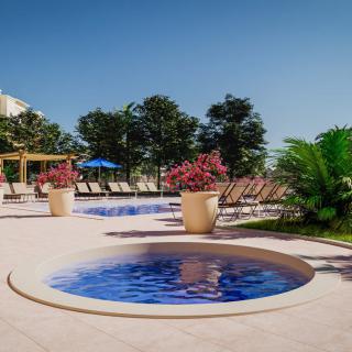 A serene outdoor pool area with lounge chairs and vibrant greenery under a clear blue sky.