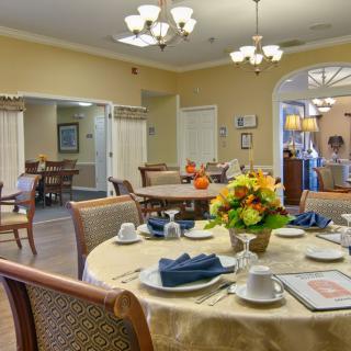 A warmly lit dining room with elegantly set tables and floral arrangements.