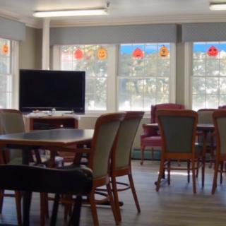 A communal room with tables, chairs, and a television.