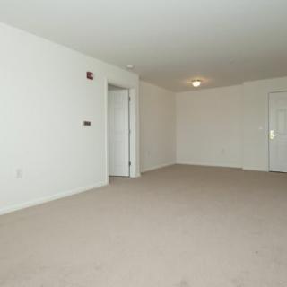 A spacious, empty room with white walls and a carpeted floor.