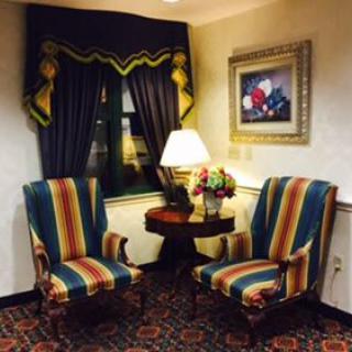 A cozy living room corner with striped chairs, a lamp on a table, and elegant curtains.