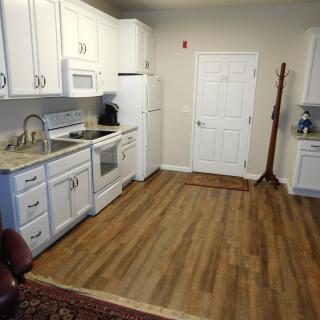 A modern kitchen with white cabinets and a wood floor.
