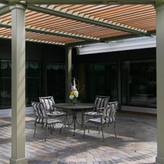 A covered patio with a dining set consisting of a round table and six chairs under a pergola.
