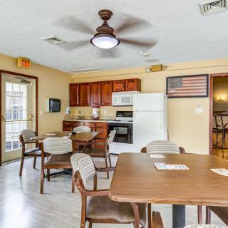 A kitchen and dining area with tables, chairs, a ceiling fan, and standard appliances like a fridge and oven.