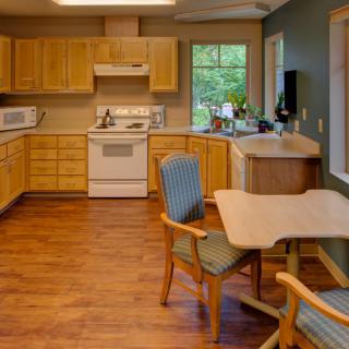 A cozy kitchen with wooden cabinets, a dining area, and a view through the window.