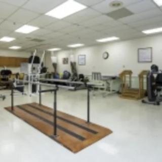 A spacious rehabilitation room equipped with various therapy and exercise machines.