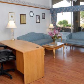 A reception area with a desk, chairs, and sofas arranged on a hardwood floor.