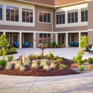 A well-maintained courtyard with landscaping and outdoor seating in front of a multi-story building.