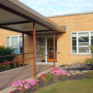 Entrance with a ramp and flowers at a brick building.