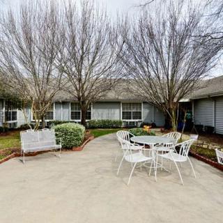 A tranquil courtyard with patio furniture and trees, surrounded by a building.