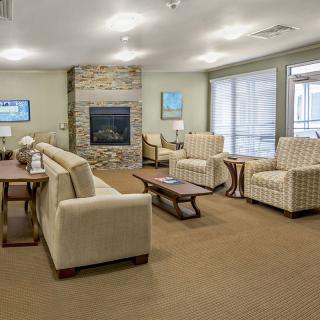 A spacious and well-designed living room featuring comfortable seating, a central fireplace, and large windows allowing natural light.