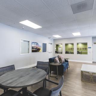 A modern interior space featuring a waiting area with tables and chairs.