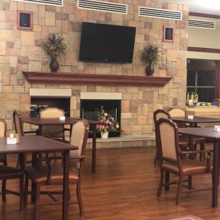 A cozy dining area featuring wooden tables and chairs, a stone fireplace, and a television.