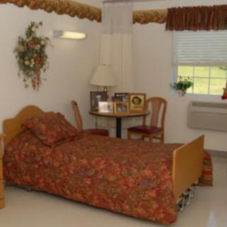 A cozy bedroom with a single bed, a small table with chairs, and a window letting in natural light.