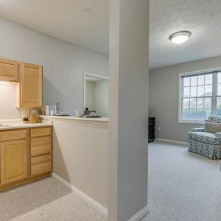 A view of a modern apartment interior showcasing a small kitchen and a cozy living room.