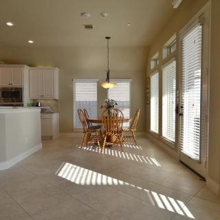 A bright and spacious kitchen and dining area with natural light filtering through the window blinds.