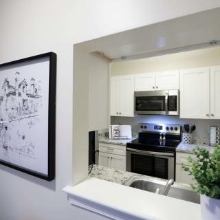 A modern kitchen with white cabinets and sleek appliances, complemented by minimalist decor and framed artwork.