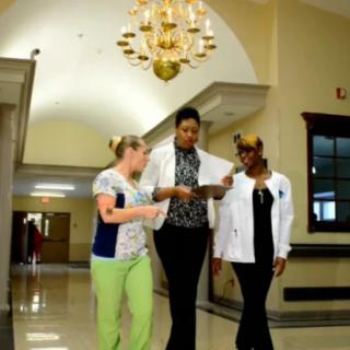 Three healthcare professionals walking down a hospital corridor, discussing a document.