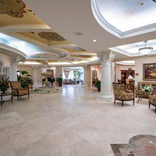 A luxurious lobby featuring marble floors, elegant seating, and detailed ceiling artwork.