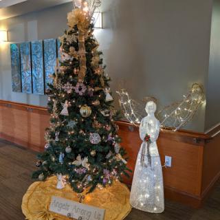 A beautifully decorated Christmas tree accompanied by a glowing angel figurine, bringing festive cheer to the space.