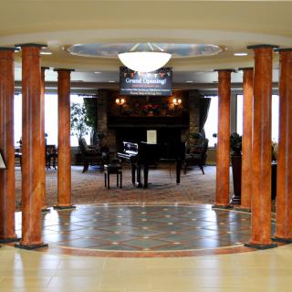 A luxurious lobby with polished columns and a grand piano at the center.