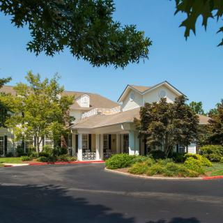 A building entrance surrounded by trees and landscaping on a sunny day.