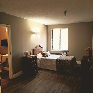 A cozy bedroom with simple decor, featuring a bed, nightstand, and window.