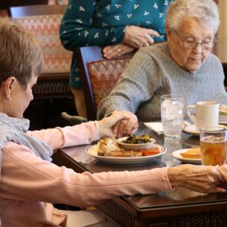 Elderly individuals sharing a meal together at a dining table.