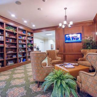 A cozy library room with comfortable seating, bookshelves, and a television.