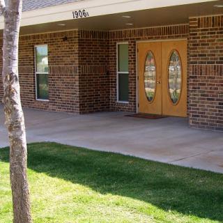 Entrance of a brick building with decorative double doors and well-maintained landscaping.