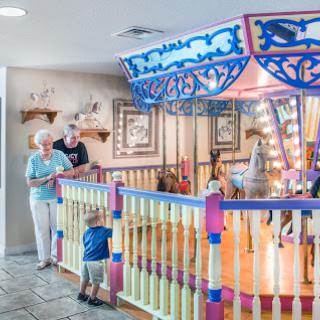 A cheerful indoor carousel where families gather, showcasing vibrant colors and a playful atmosphere.