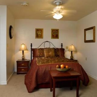 A cozy bedroom with a neatly made bed, side lamps, and decorative paintings.