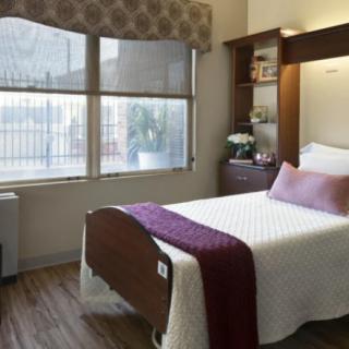 A neatly arranged bedroom with a single bed, a window, and a nightstand.