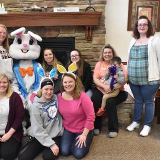 A group of people posing indoors with someone dressed as the Easter bunny.
