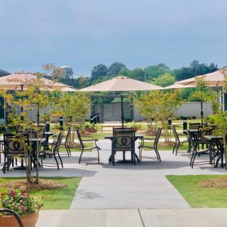 A scenic outdoor patio area with tables, chairs, and umbrellas surrounded by greenery.