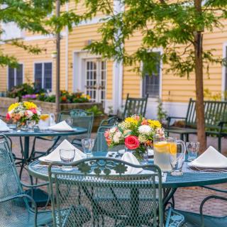 A charming outdoor patio setting with tables adorned with colorful floral arrangements.