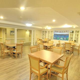 A spacious dining area with wooden tables and chairs, warmly lit.