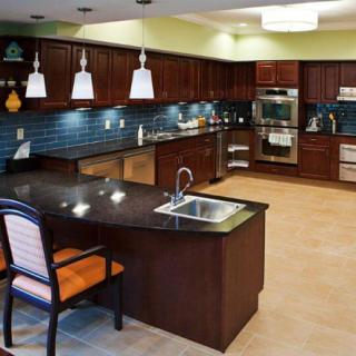 A modern kitchen featuring dark cabinets, a granite island with seating, and stainless steel appliances.