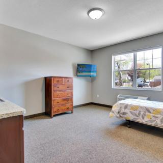 A minimalist bedroom featuring a bed, dresser, and large window.