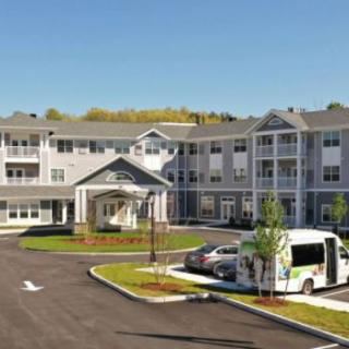 A modern residential building with a parking area and landscaped surroundings.