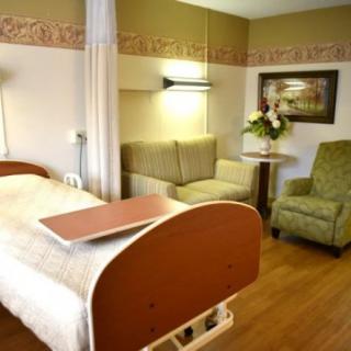 A well-furnished hospital room with a patient bed and seating area.