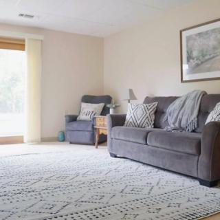 A cozy living room with a grey sofa, an armchair, and a patterned rug.