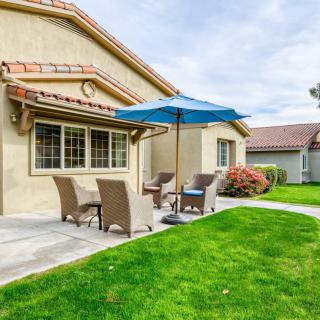 A cozy backyard patio with outdoor furniture and a blue umbrella.