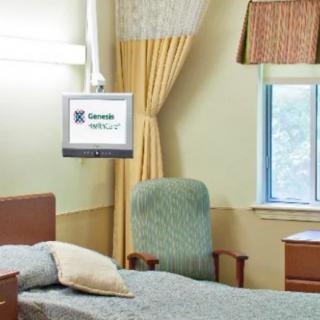 A tidy hospital room featuring a bed, a comfortable chair, and a wall-mounted television near the window.